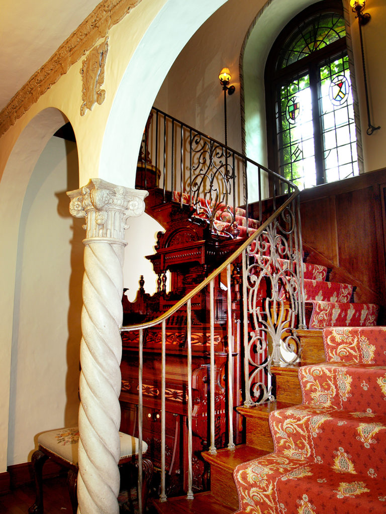 Main stairway for a Tudor estate, arched leaded glass windows.