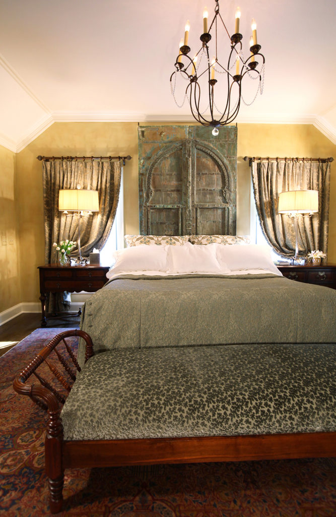 Master bedroom with antique doors as headboard and daybed at foot of bed
